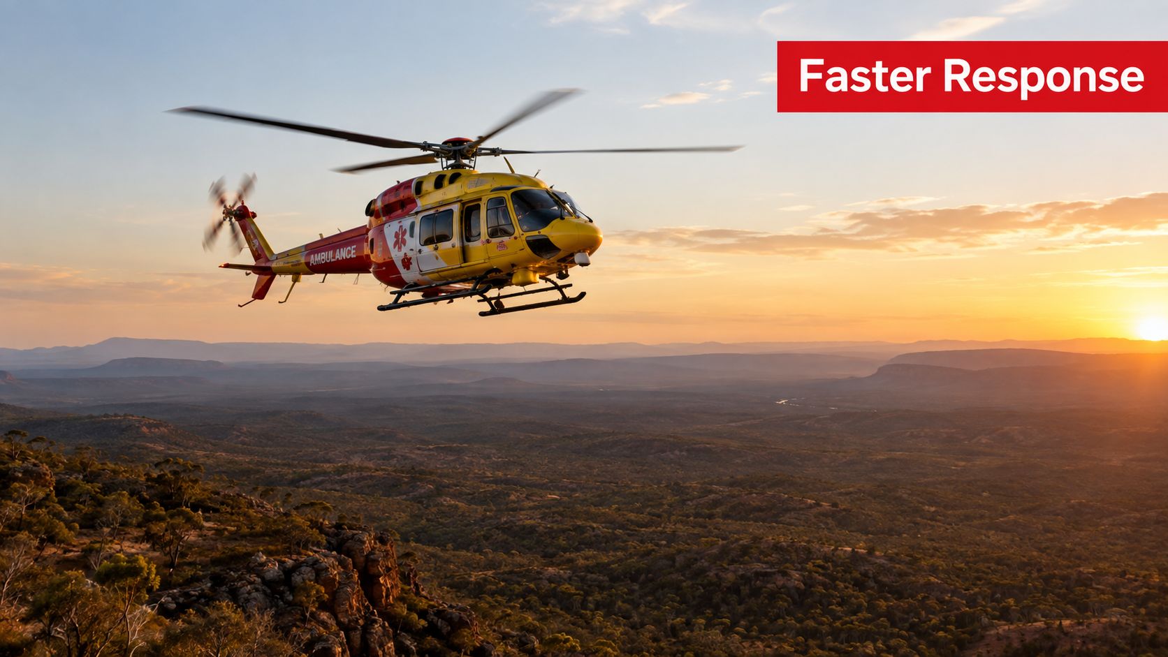 A bright yellow and red medical ambulance helicopter flying over a rocky landscape during sunset.